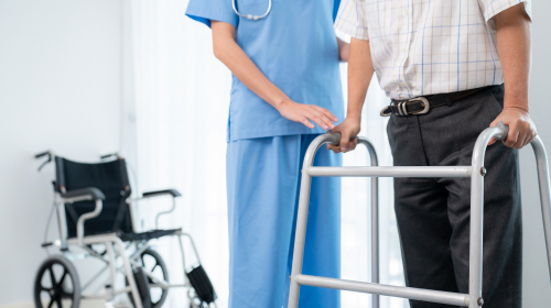 Close-up image of a healthcare professional helping an elderly man with a walker representing product suggestions & procurement.